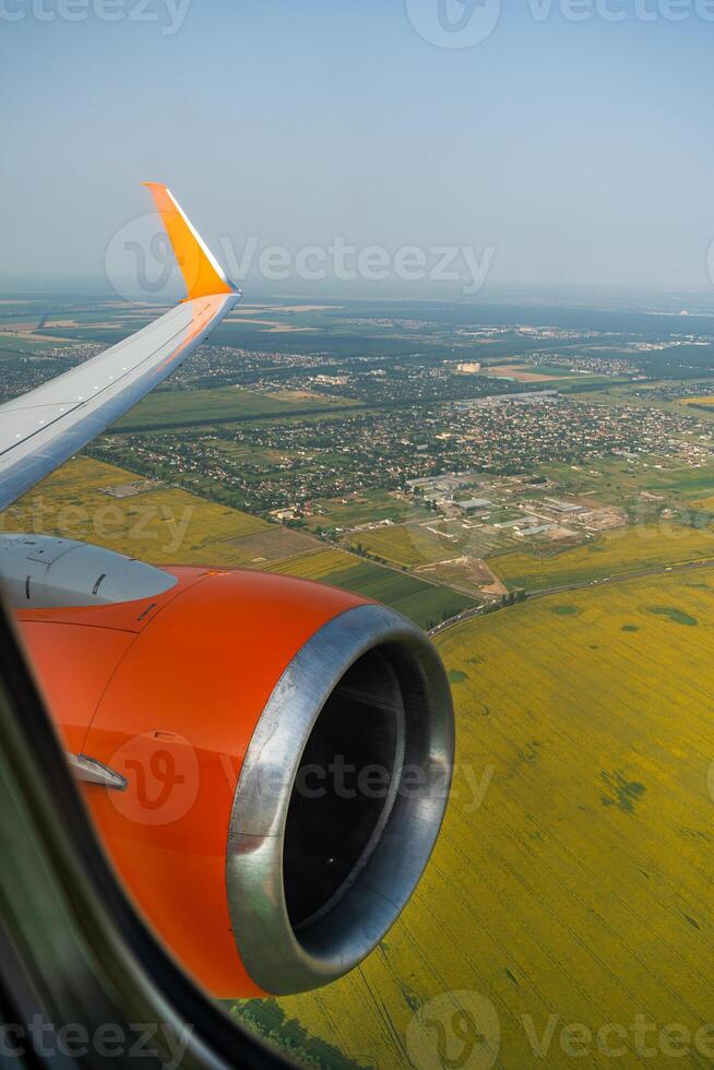 Land view through the airplane window. Fields, roads, rivers from a bird's eye view. Porthole. Look out the window of a flying plane. Top view of the ground photo