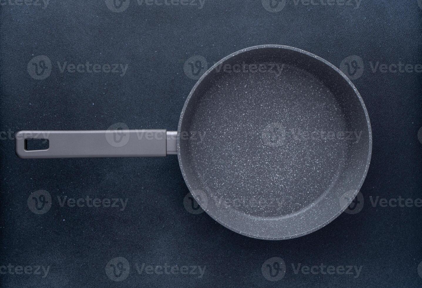 New granite frying pan on a gray background, top view. Empty fry pan with handle. photo