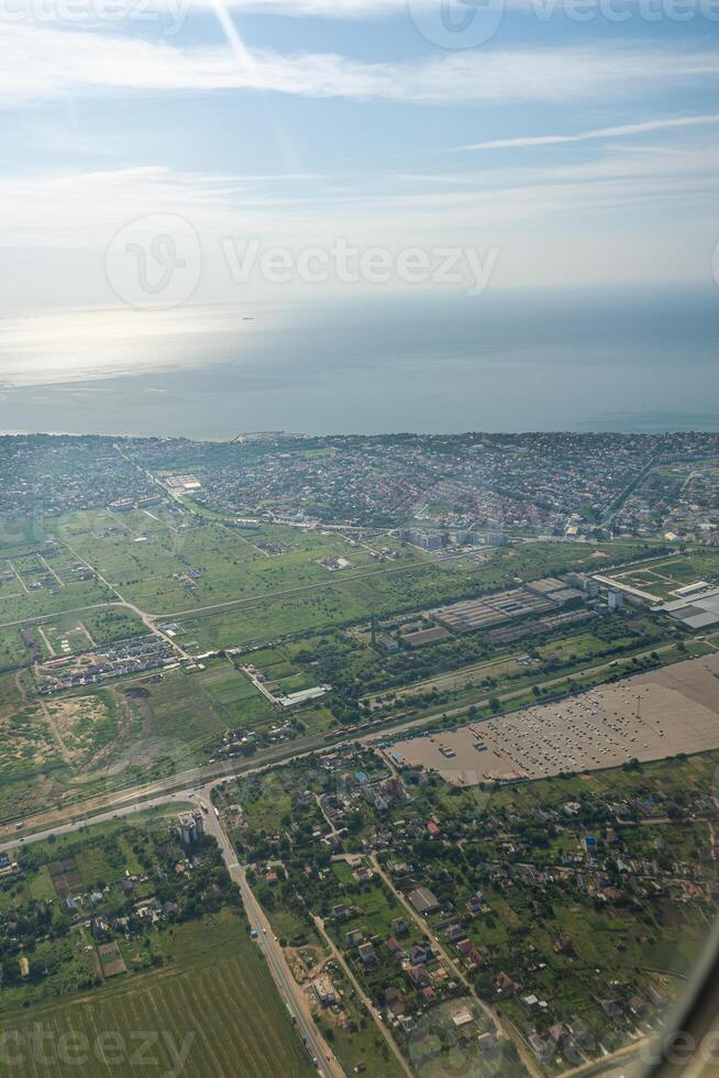 Land view through the airplane window. Fields, roads, rivers from a bird's eye view. Porthole. Look out the window of a flying plane. Top view of the ground photo