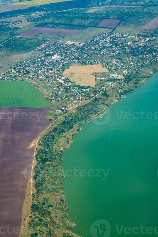 Land view through the airplane window. Fields, roads, rivers from a bird's eye view. Porthole. Look out the window of a flying plane. Top view of the ground photo