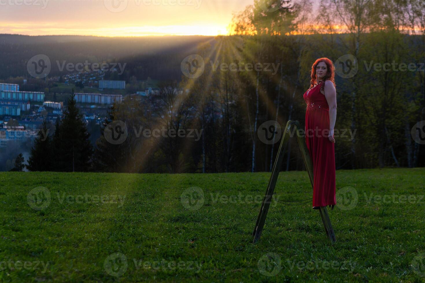 woman in a red dress and a ladder in a sunset photo