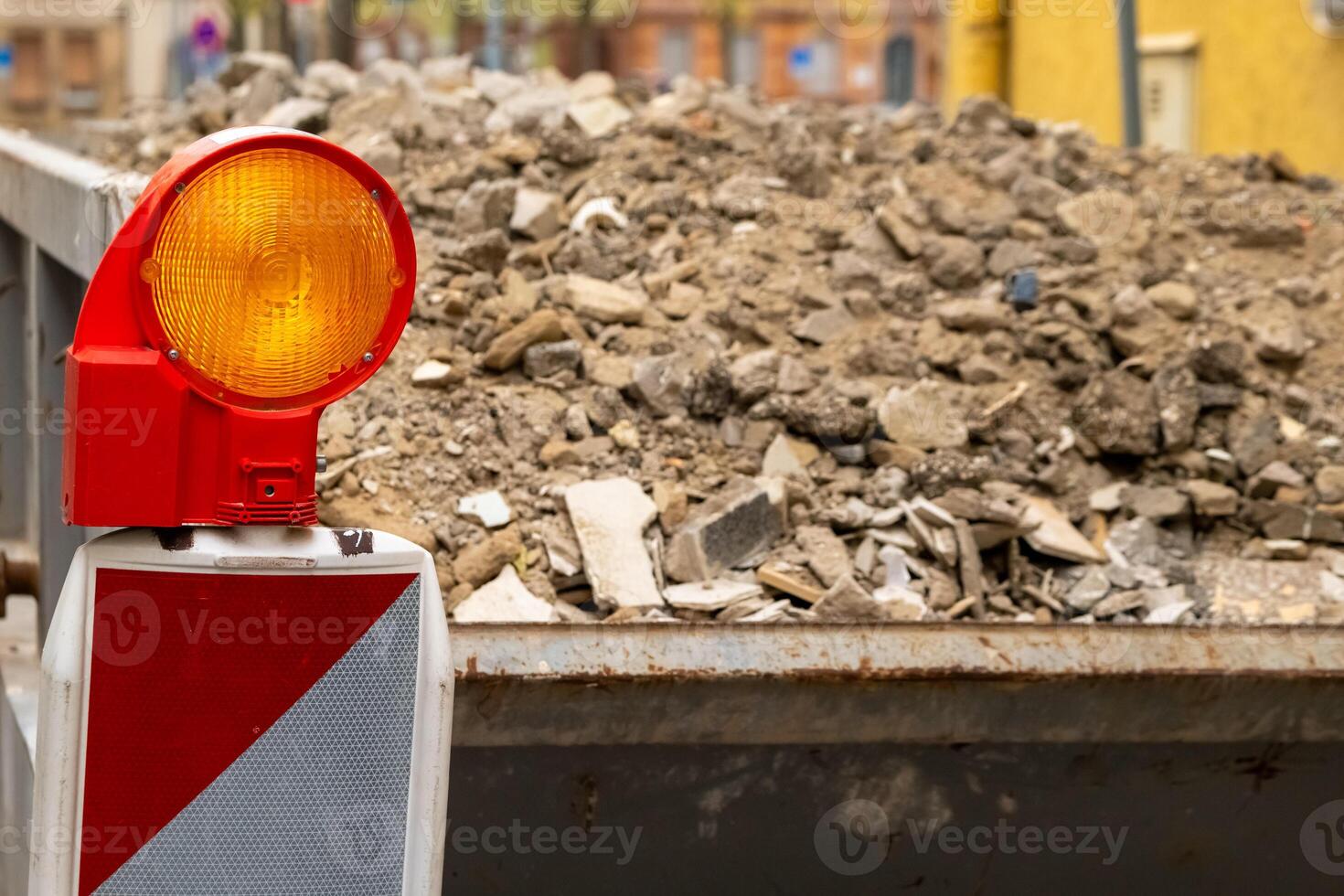 yellow and red construction lamp in front of a pile of rubble photo