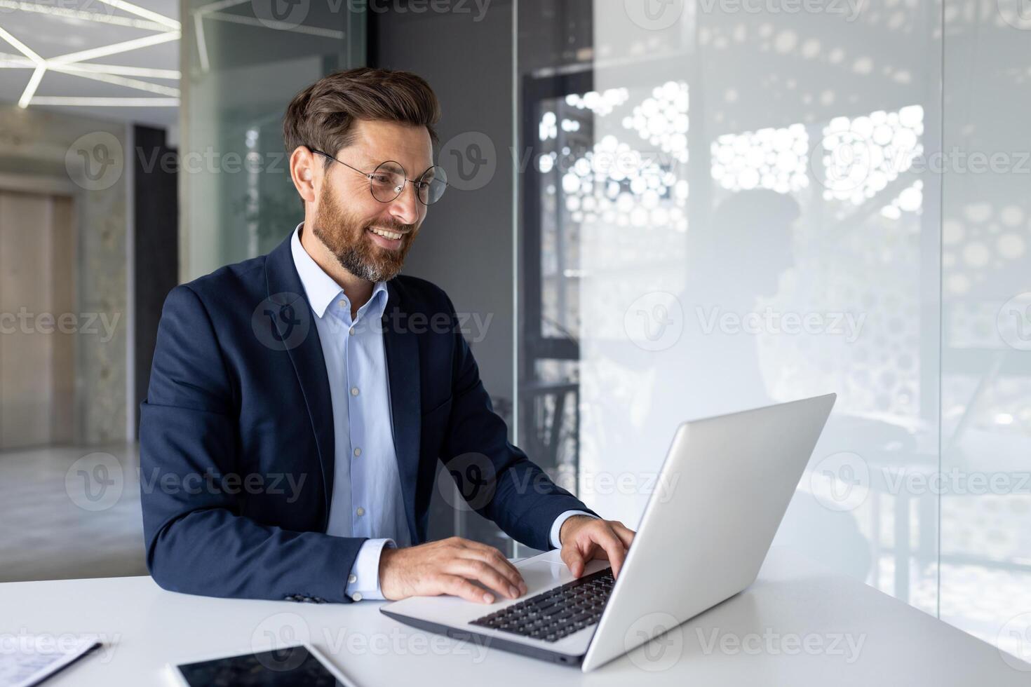 sonriente empresario trabajando en ordenador portátil en moderno oficina, reflejando productividad, éxito y profesional contentamiento. foto