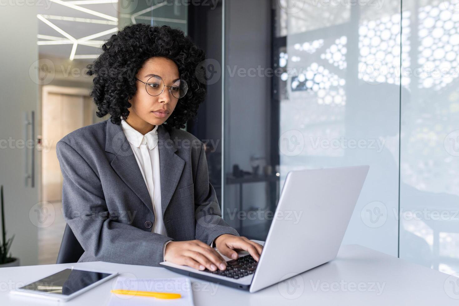 grave concentrado y pensando mujer de negocios dentro oficina a lugar de trabajo mecanografía en computadora portátil, hembra jefe trabajando con computadora, resolviendo técnico financiero tarea. foto