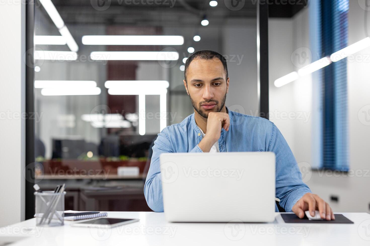 Focused professional using a laptop at an organized workspace with modern design in a corporate office. photo