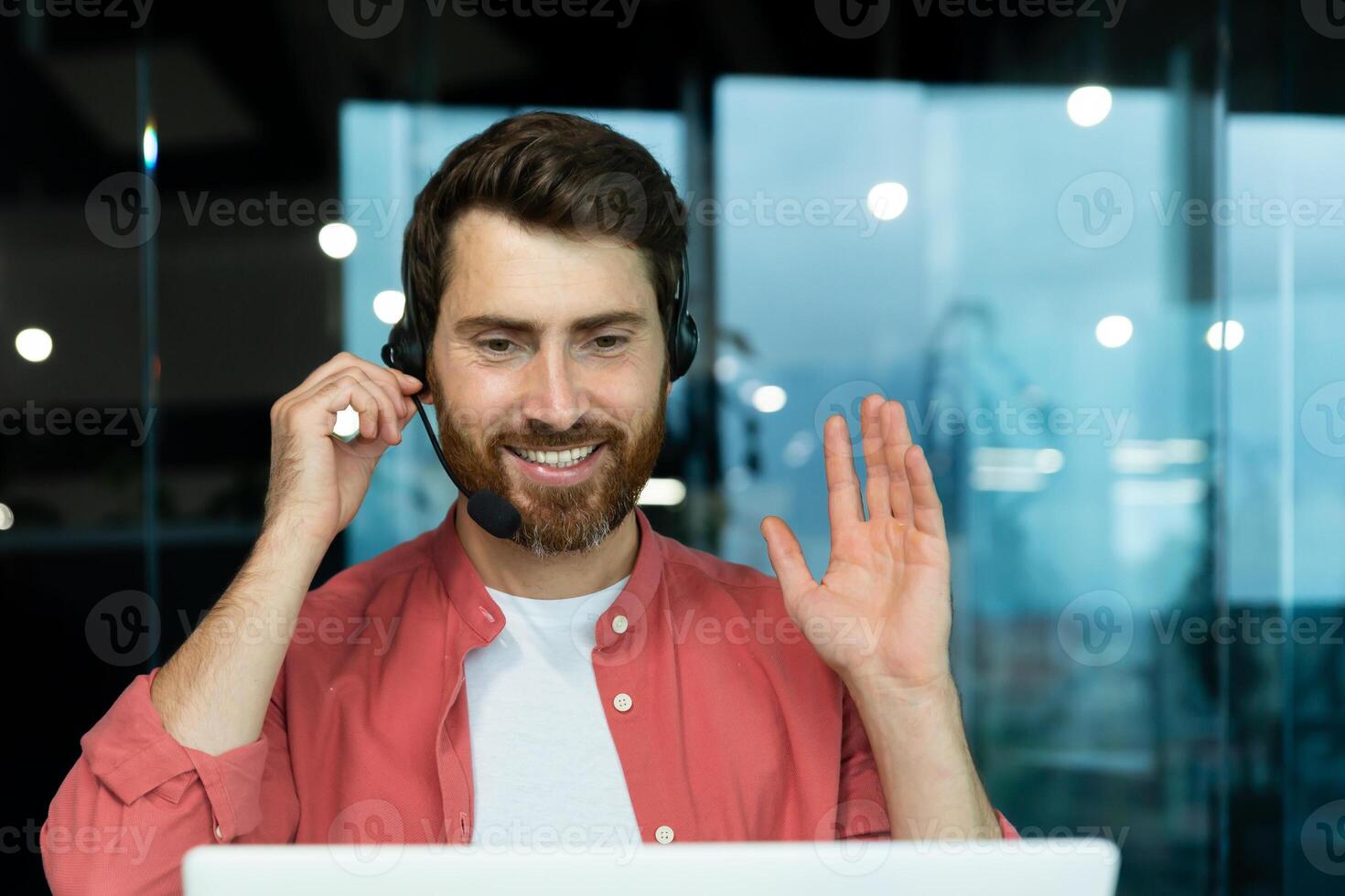 Customer service representative with headset phone consults customer buyer, joyful man uses laptop for call, businessman in shirt at workplace inside office happy and smiling. photo