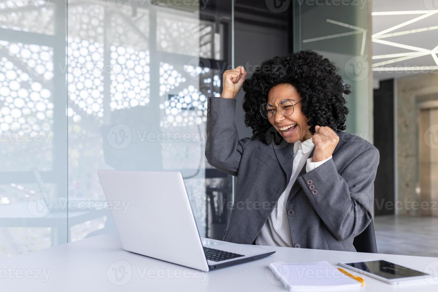 exitoso africano americano mujer a lugar de trabajo dentro oficina, negocio mujer ganador tiene bueno resultado y logro a lugar de trabajo, leyendo notificación utilizando ordenador portátil. foto