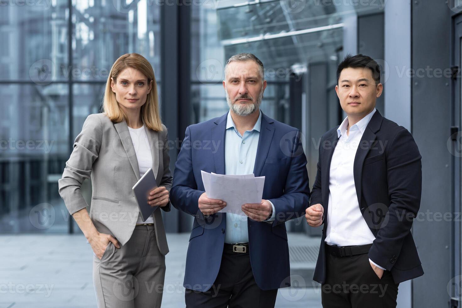 A team of experienced team leaders and specialists, a diverse group of business people, three people in business clothes are serious and focused in business clothes looking at the camera photo