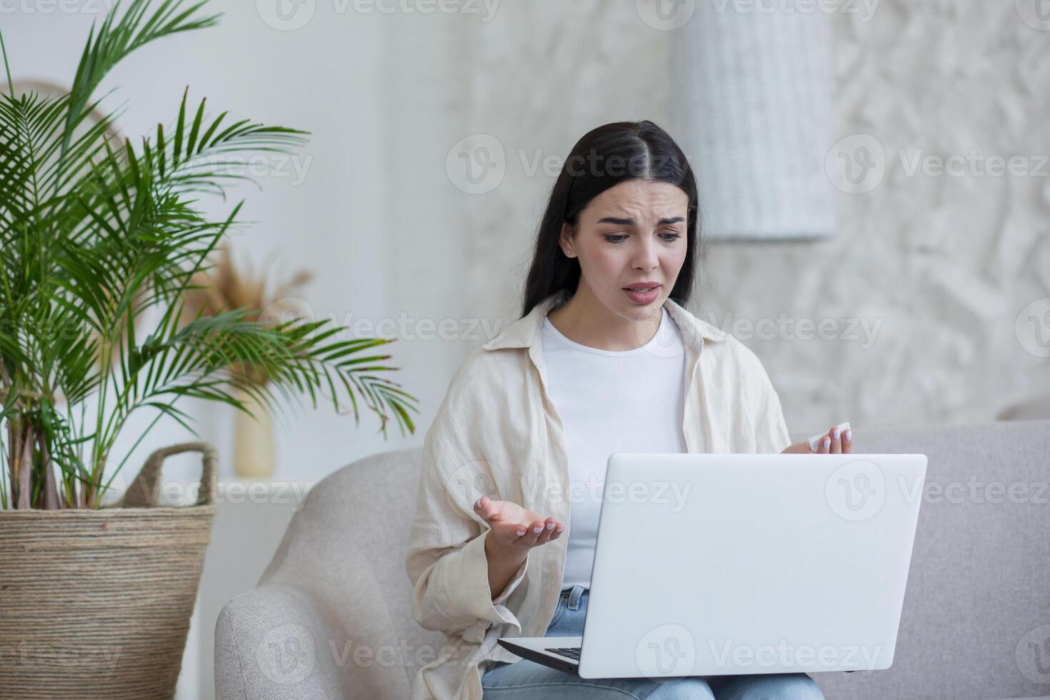 Online psychotherapy. A young worried woman is sitting at home with laptop photo