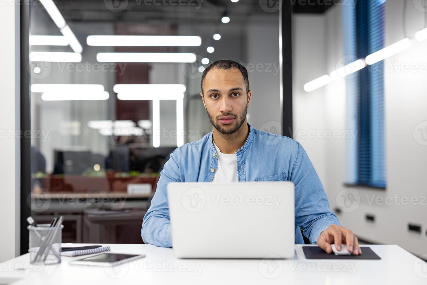 Focused male professional using a laptop at a modern workspace, embodying determination and efficiency. photo