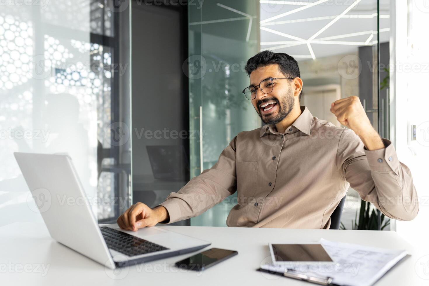Successful businessman inside office celebrating victory and triumph, man reading happy news from laptop, entrepreneur working at workplace, satisfied with achievement results. photo