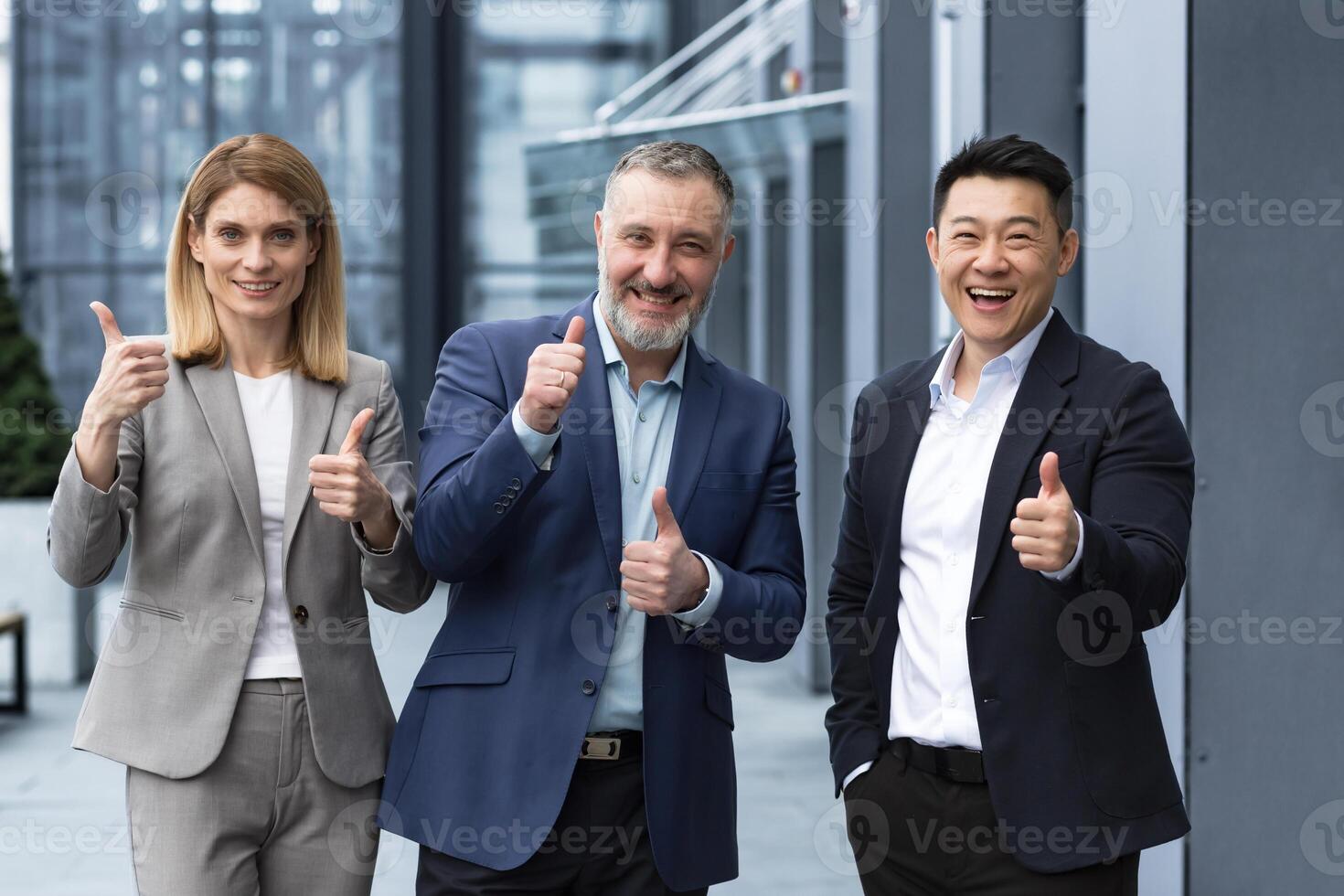 Cheerful dream team, senior and experienced IT professionals in business suits smiling and happy holding thumb up and looking at camera, diverse group of project managers outside office building. photo