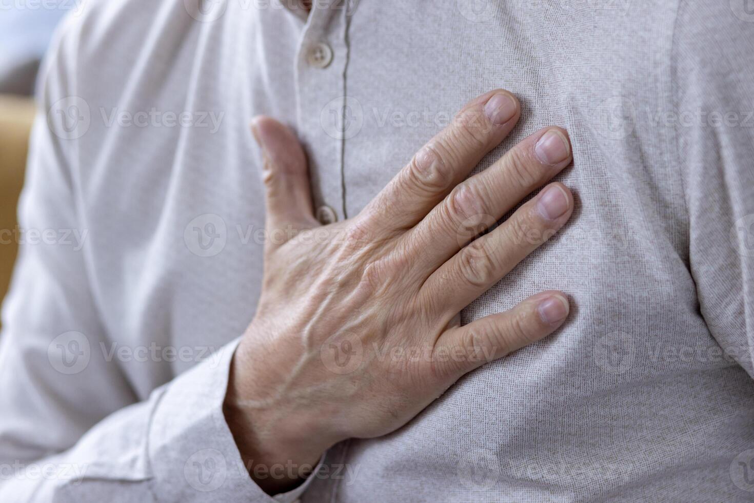 esta imagen capturas un de cerca ver de un de edad mediana hombre sensación su latido del corazón. el atención es en su mano y el textura de su camisa, transporte un sentido de salud y bienestar. foto