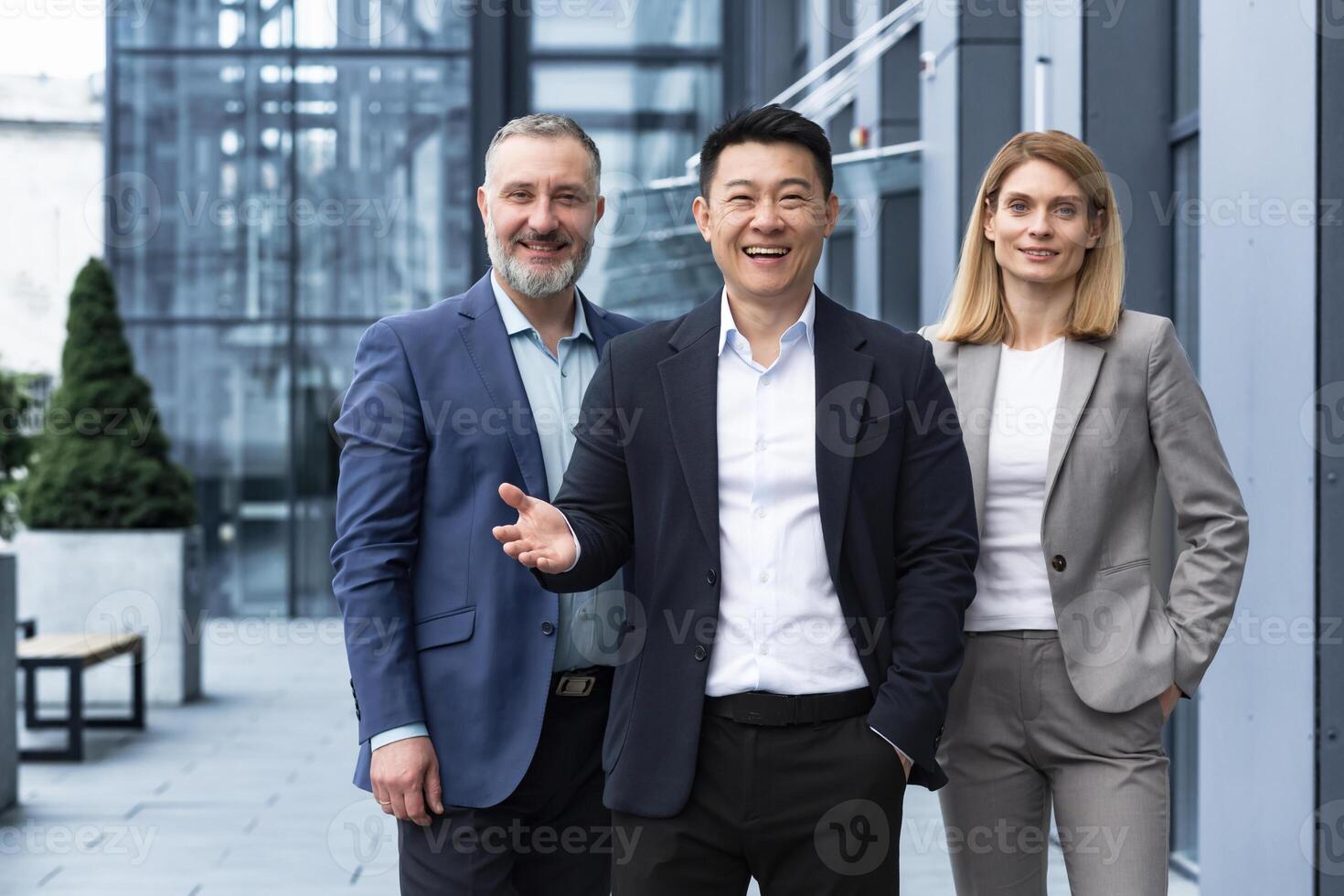 exitoso diverso negocio equipo, Tres trabajadores sonriente y mirando a cámara, sueño equipo con asiático jefe fuera de oficina edificio, colegas en negocio trajes foto