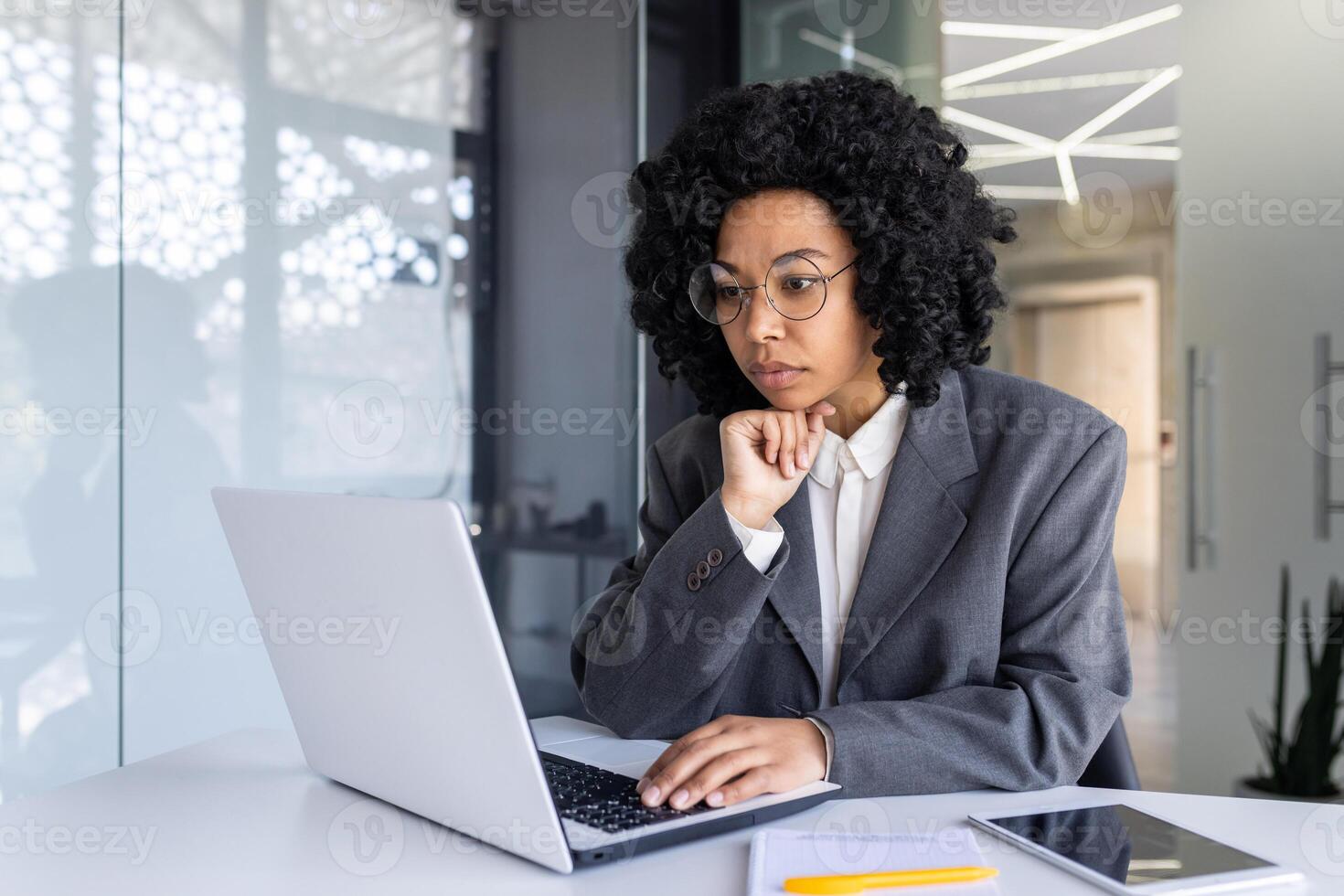 grave concentrado y pensando mujer de negocios dentro oficina a lugar de trabajo mecanografía en computadora portátil, hembra jefe trabajando con computadora, resolviendo técnico financiero tarea. foto