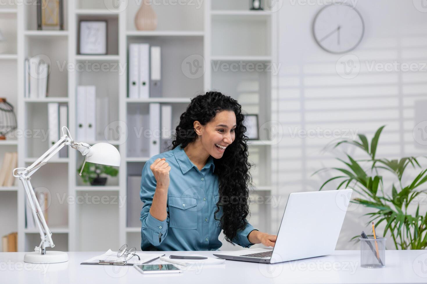 alegre Hispano mujer trabajando desde hogar, celebrando un negocio logro en su acogedor hogar oficina configuración. foto