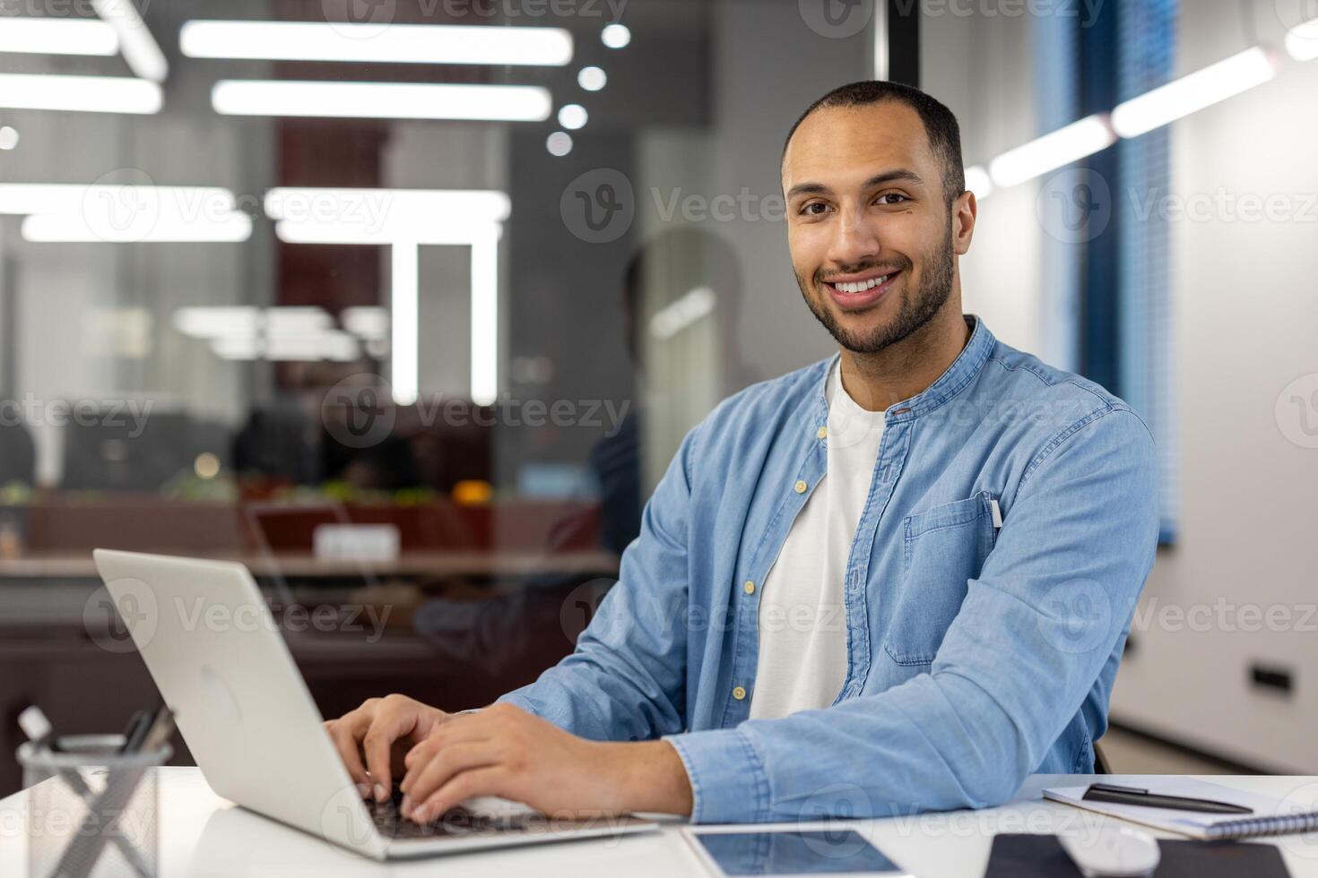 Focused professional engaging with a project on his laptop. The contemporary office environment highlights productivity and a business atmosphere, suitable for corporate themes and professional settings. photo