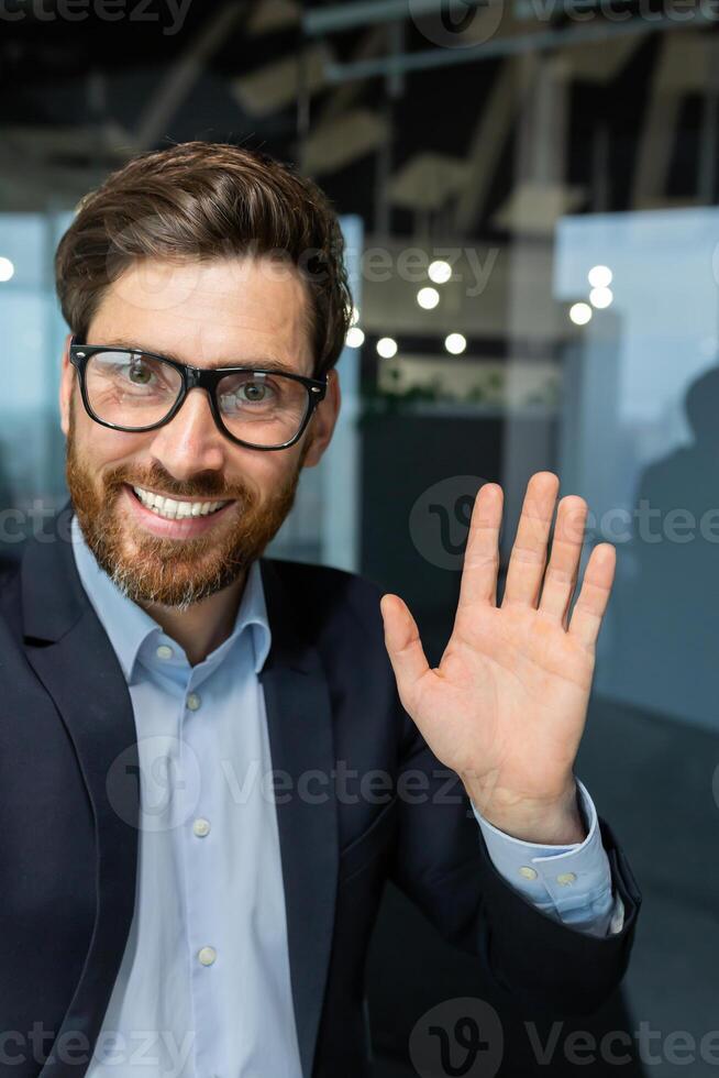 llamada exitoso y contento maduro jefe hablando a amigos de forma remota, empresario trabajando dentro moderno oficina utilizando teléfono inteligente a comunicar, en línea amigos conversación. foto