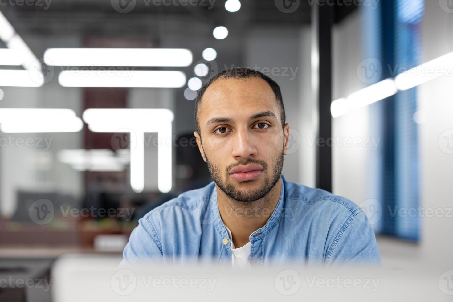 un joven hombre enfocado en su trabajo en un contemporáneo oficina, encarnar el espíritu de profesionalismo y Dedicación en un corporativo ambiente. foto