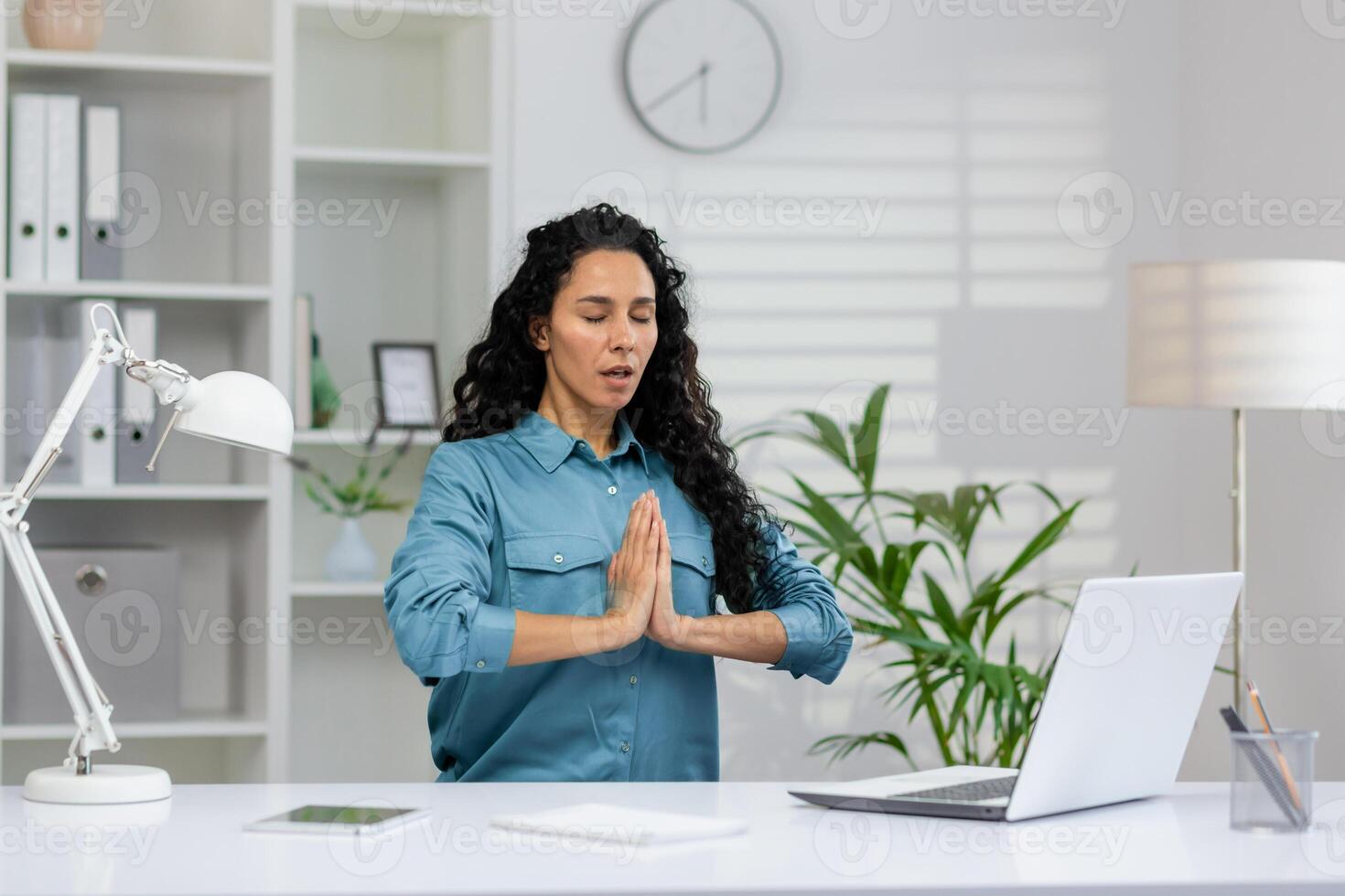 un mujer en un calma estado de meditación a su lugar de trabajo, buscando atención plena en medio de su ocupado dia de trabajo alrededores. foto