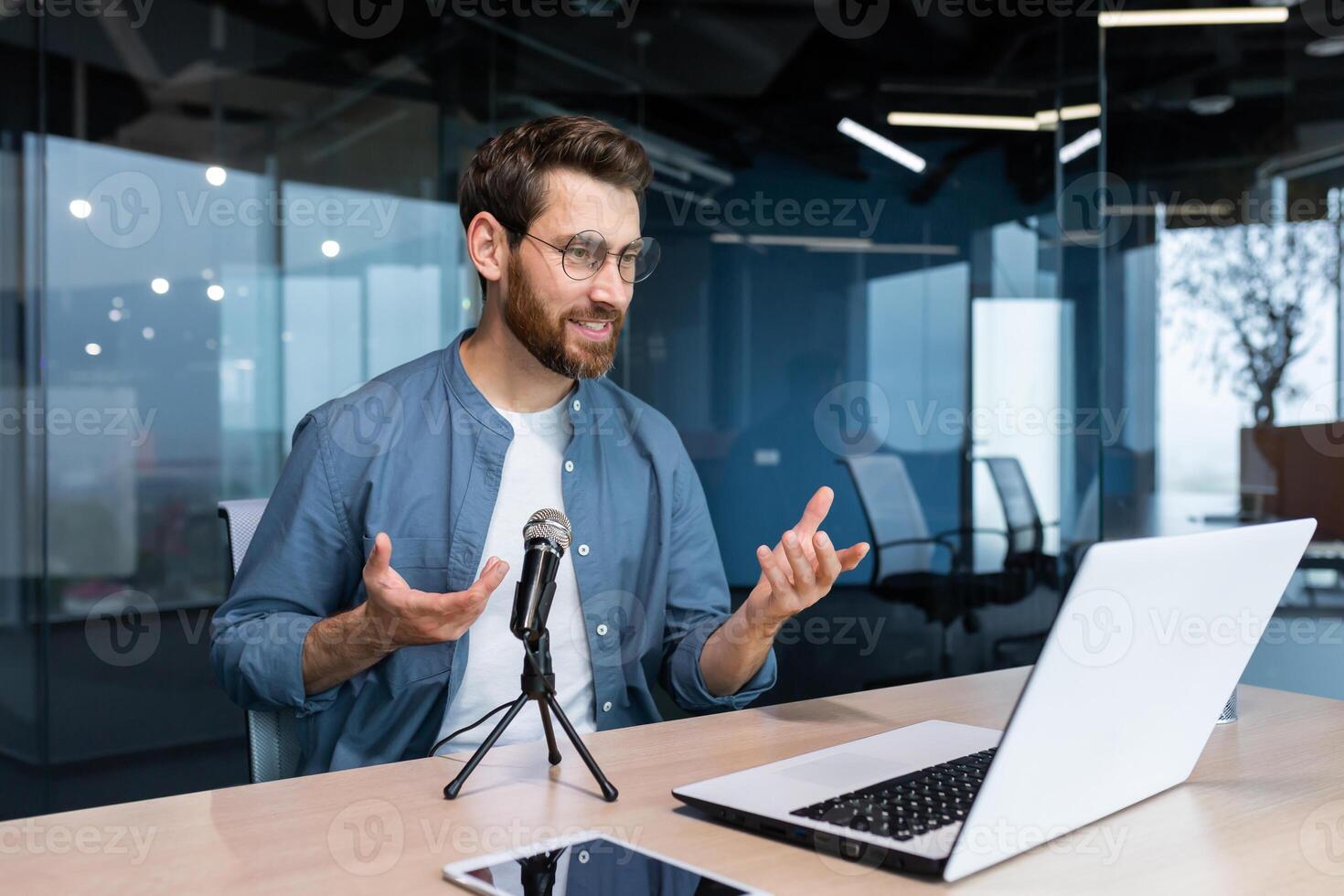 Business coach inside office recording audio podcast, businessman working at laptop using professional microphone and laptop for online radio, and training Remote. photo