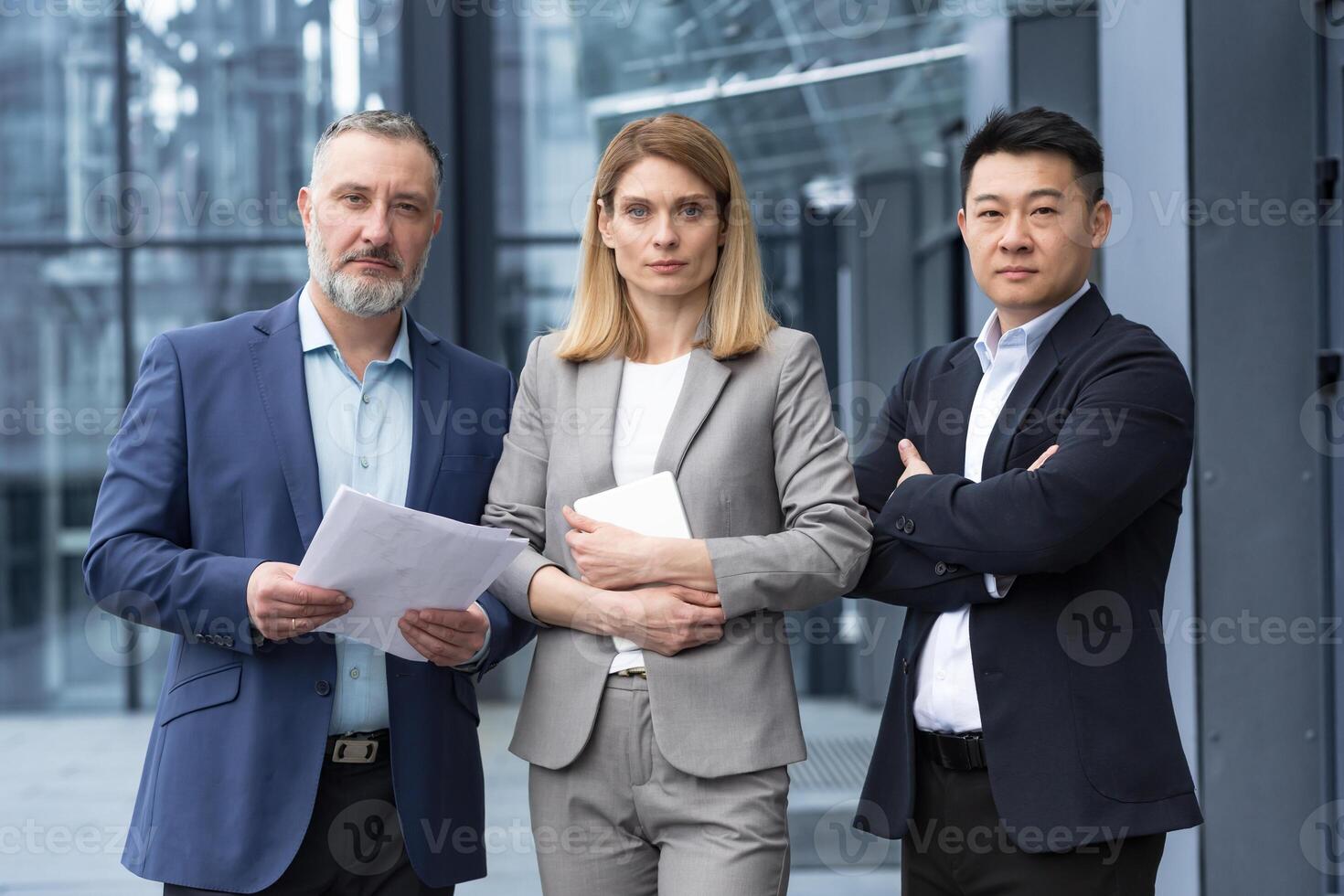 A team of experienced team leaders and specialists, a diverse group of business people, three people in business clothes are serious and focused in business clothes looking at the camera photo