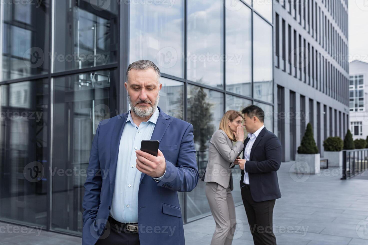 Two colleagues are gossiping at background behind the boss. workmate about bullying problem at work place in office in the break outside Male Coworkers employees man and woman Whispering Behind Back. photo
