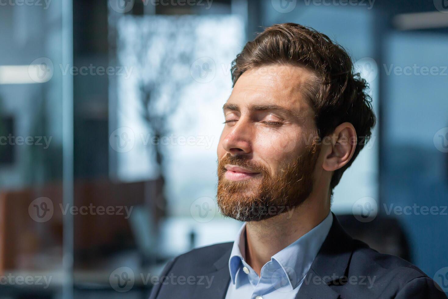 Close-up photo. Portrait of a handsome young man who closed his eyes and rests at the workplace. Sitting relaxed in the office. photo