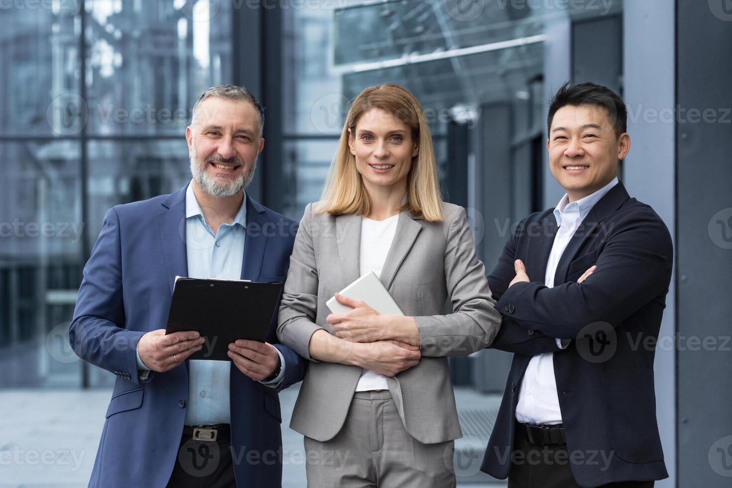 Successful dream team, diverse business group of asian man and business woman smiling and looking at camera, colleagues with crossed arms outside office building, professionals investors and bankers photo