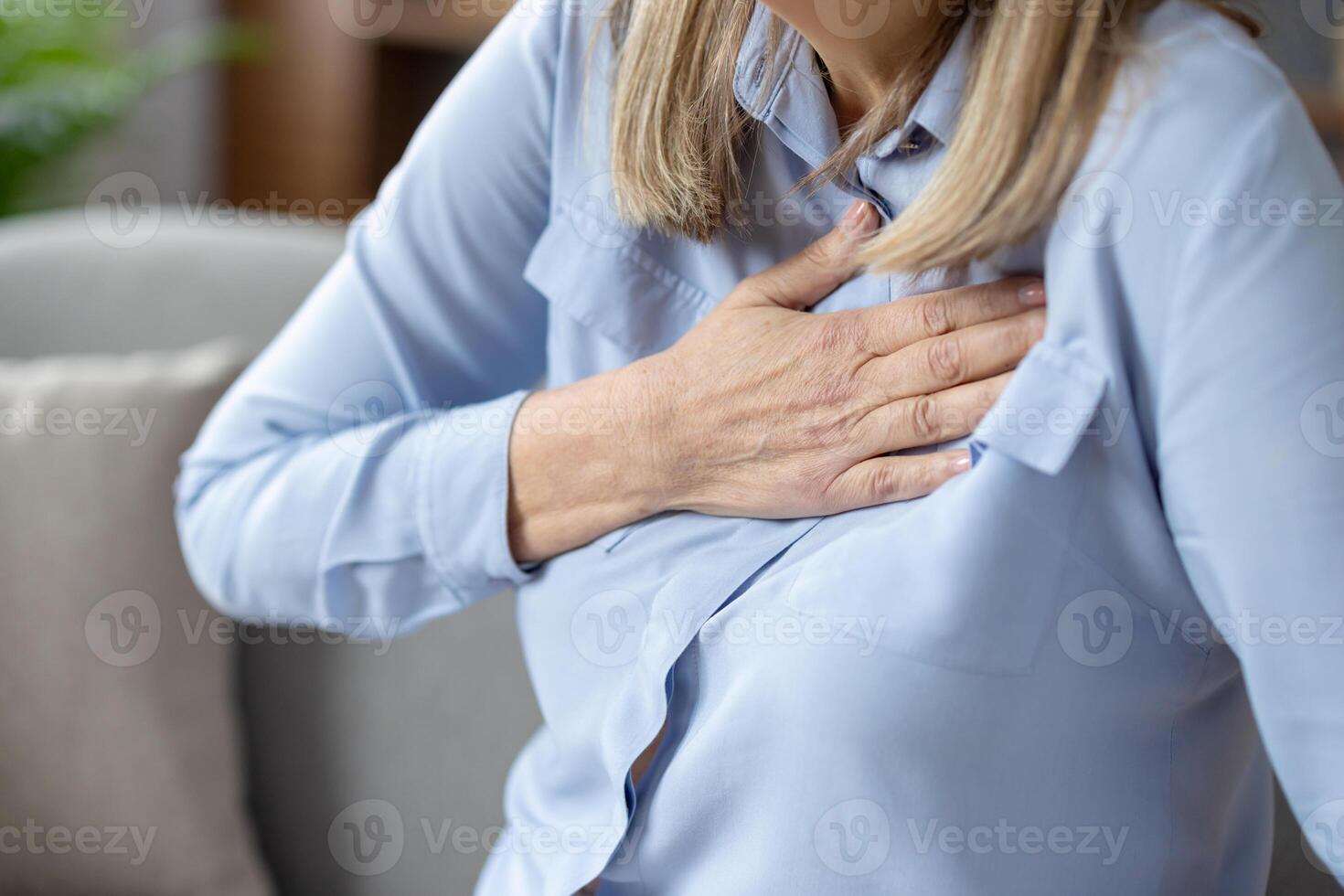 de cerca imagen de un mayor mujer experimentando incomodidad y participación su pecho, posiblemente indicando corazón problemas o un corazón ataque. foto