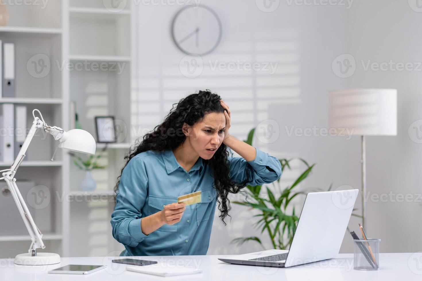 Worried Hispanic businesswoman working from home office reacts to a fraud or error on her credit card. photo