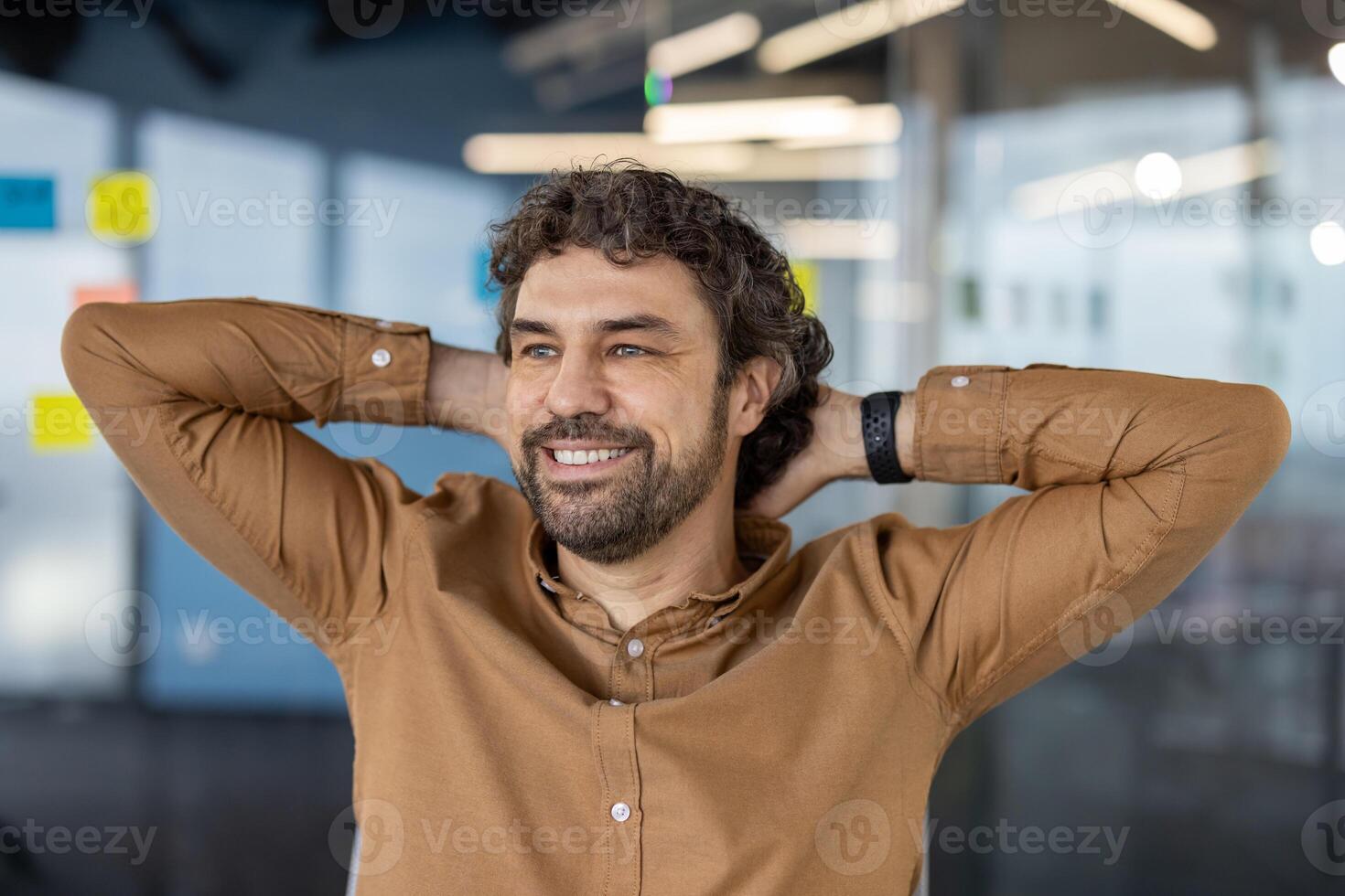 Relaxed caucasian male stretching back and resting head on hands while observing office life from cabinet. Satisfied executive keeping balance of stress and making break from work for resting. photo