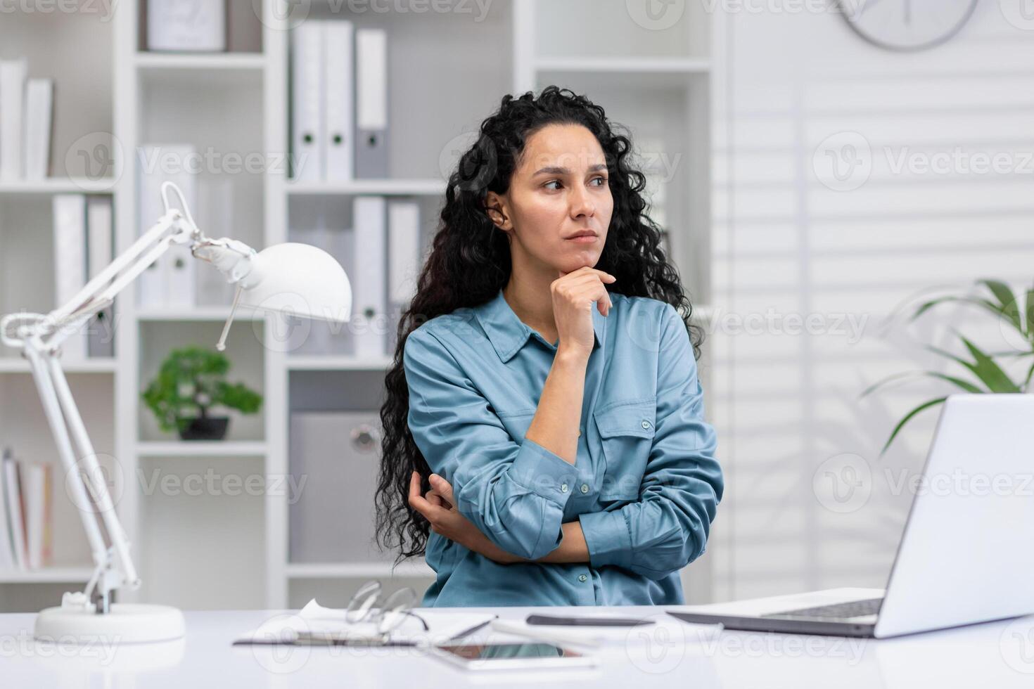 Pensive Latina businesswoman in home office setting, portraying determination and professionalism while at work. photo