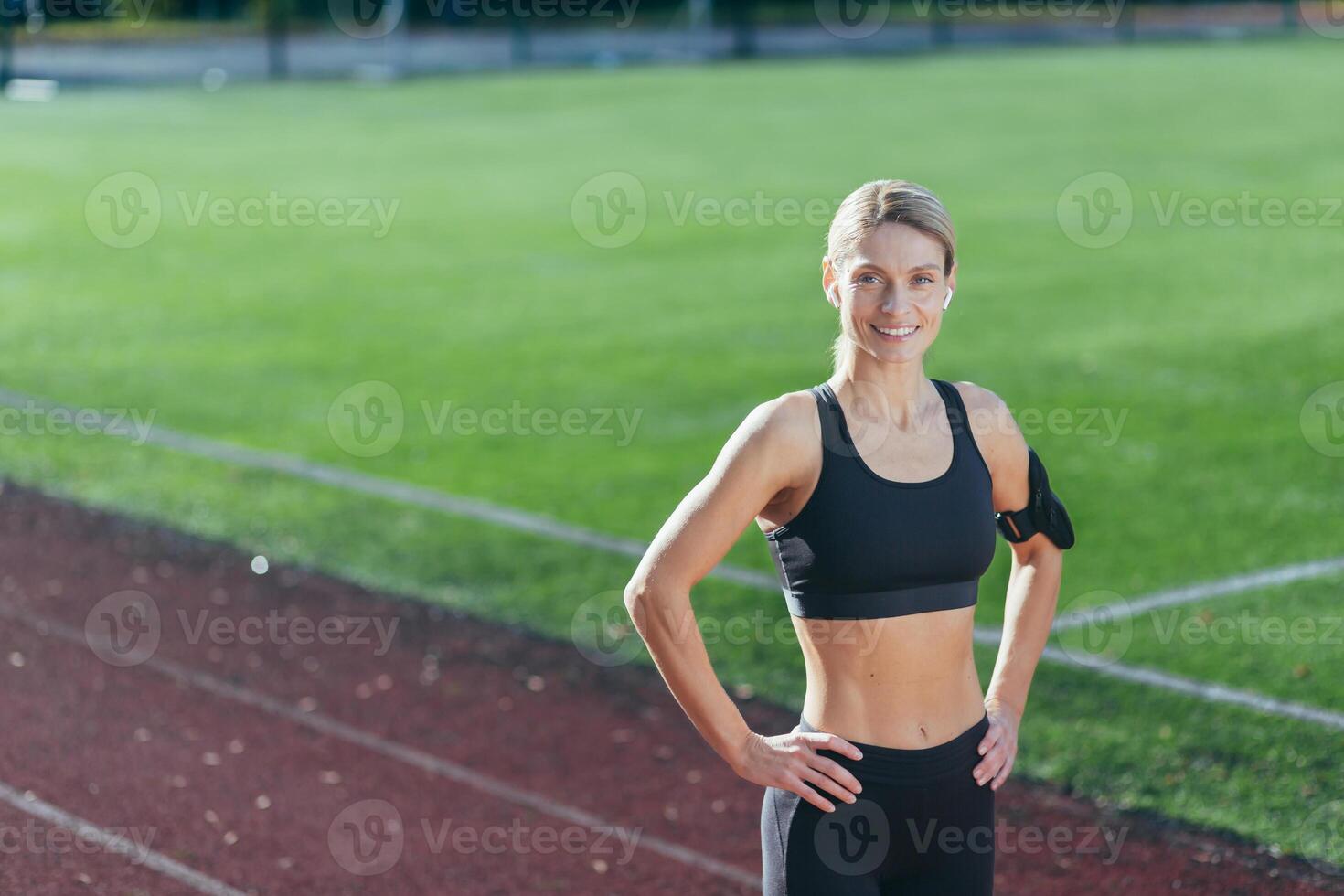 retrato de deportista en ropa de deporte a estadio, rubia sonriente y mirando a cámara, mujer antes de Mañana rutina de ejercicio y ejercicio y aptitud física. foto