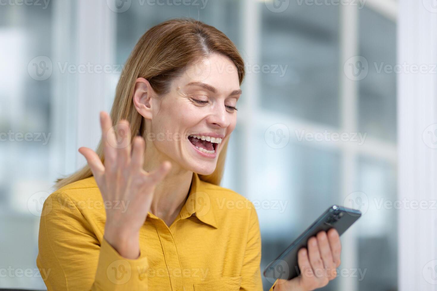 alegre exitoso negocio mujer celebrando victoria éxito, mujer jefe recibido en línea notificación en teléfono, financiero dentro oficina a lugar de trabajo, utilizando aplicación en teléfono inteligente foto