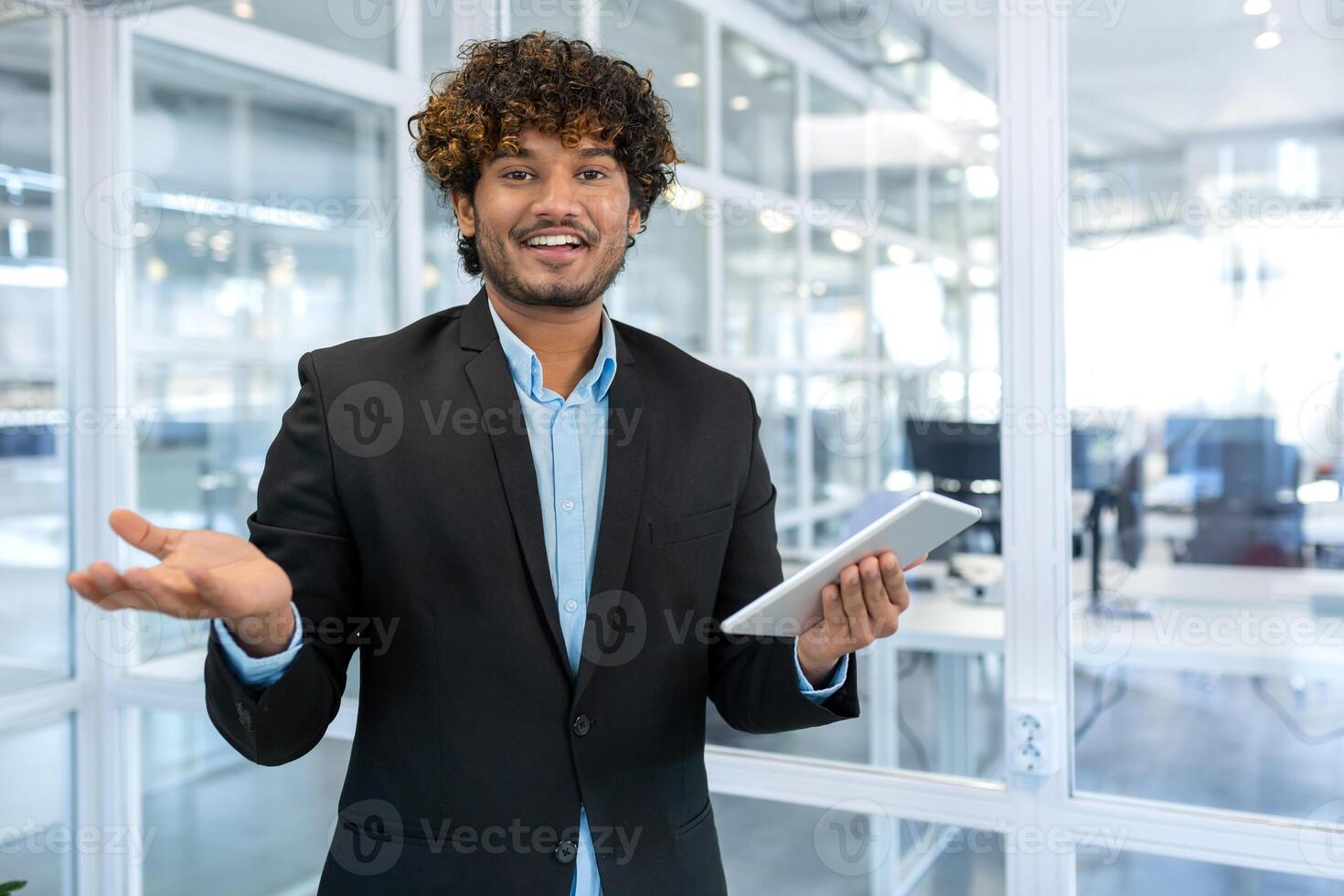 joven y exitoso masculino programador, retrato de hombre ingeniero con tableta computadora puesta en marcha trabajador trabajando dentro oficina edificio utilizando tableta para pruebas aplicaciones sonriente mirando a cámara foto