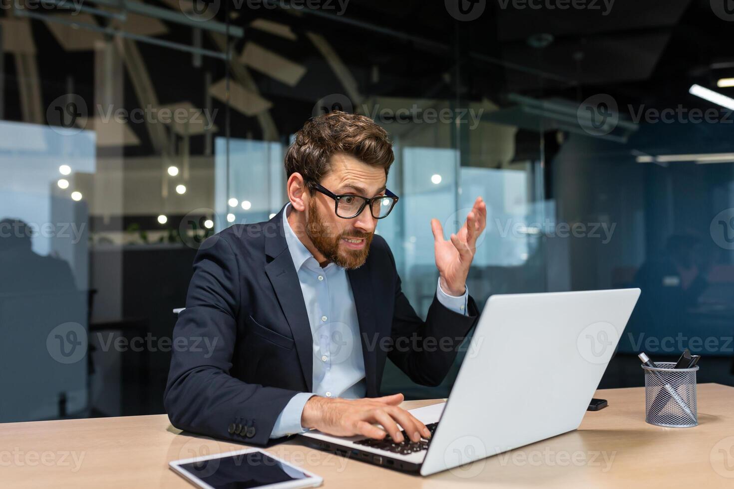 Angry mature boss got error laptop not turning on, program not working, senior man working on computer inside modern office building, businessman in glasses and business suit. photo