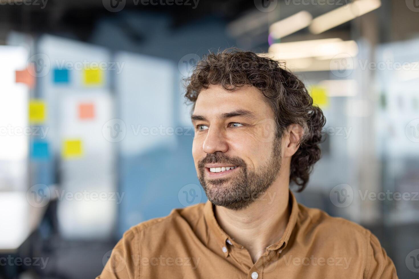 Joyful successful businessman close-up pensive and dreamy looking out window, smiling, mature experienced man at workplace inside office. photo