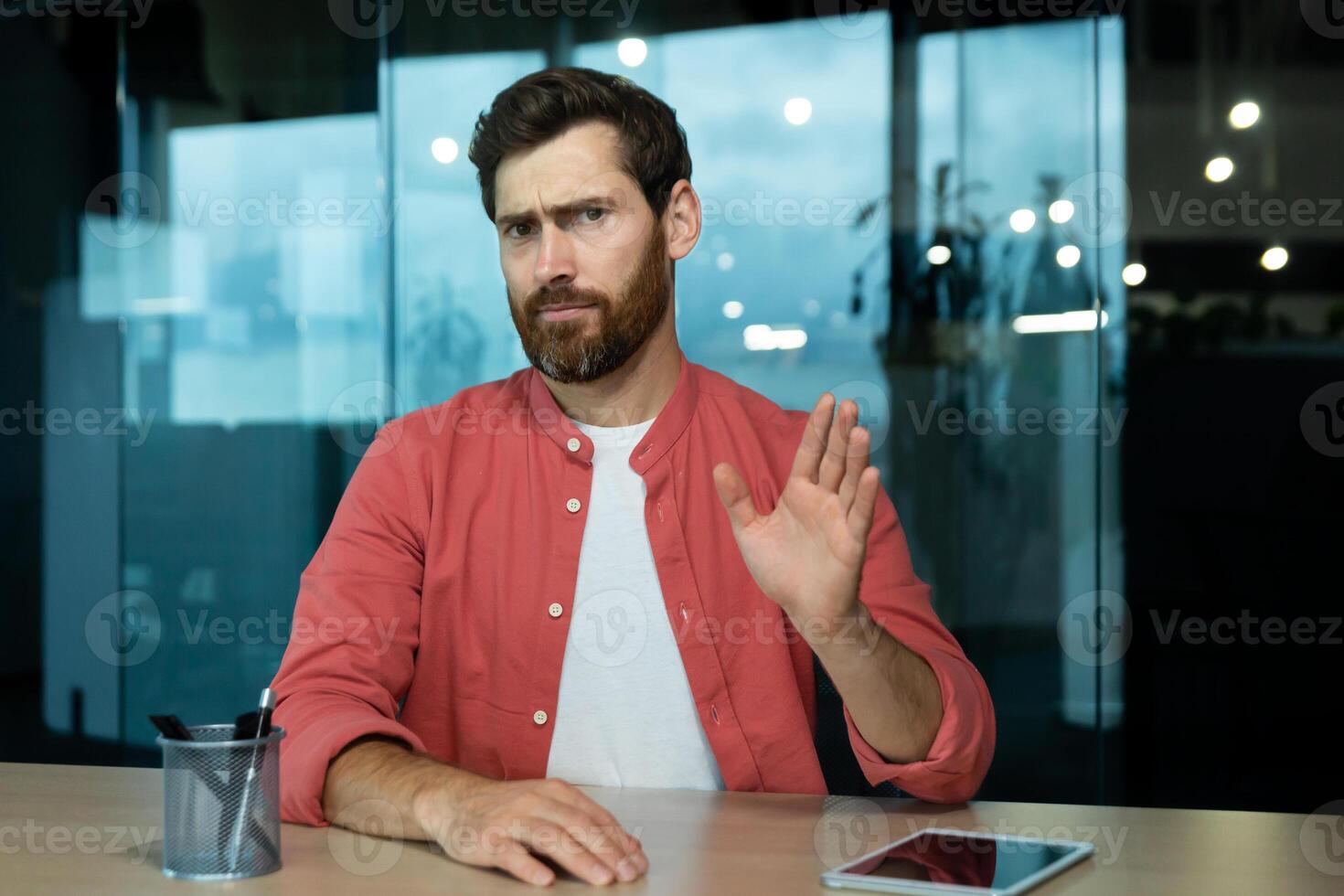 Upset unhappy and sad man inside office at workplace talking with colleagues and partners using call, remote meeting web camera view. photo