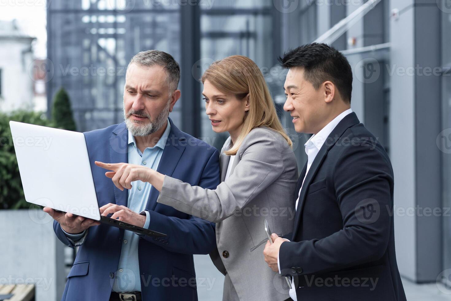 exitoso negocio equipo, Tres colegas empresario y mujer de negocios fuera de oficina edificio que se discute Actual planes y gestión, mirando a ordenador portátil pantalla, que se discute y consultante foto