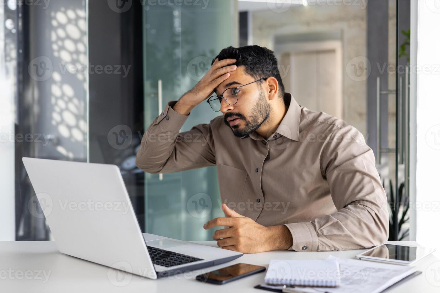 Upset and disappointed businessman at workplace got negative financial results, unsatisfied man working inside office at workplace with laptop. photo
