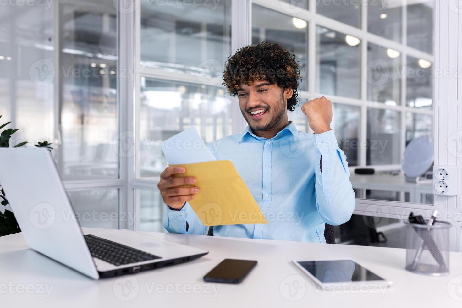 empresario celebrando victoria y éxito, recepción correo sobre con bueno Noticias notificación, Hispano leyendo documento y contento participación mano arriba triunfo gesto, hombre a lugar de trabajo dentro oficina. foto