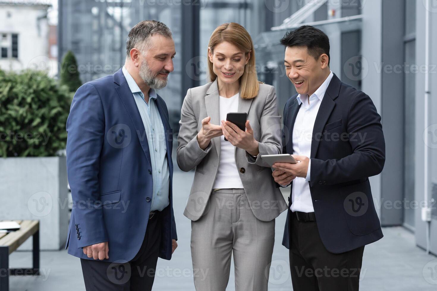 Tres eso especialistas empresarios fuera de oficina edificio acecho en colegas teléfono, contento y sonriente descansando en descanso desde trabajo foto