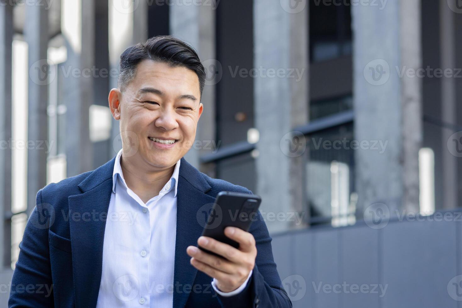 A well-dressed businessman in a suit uses his mobile phone, potentially dealing with work matters in a city environment. photo