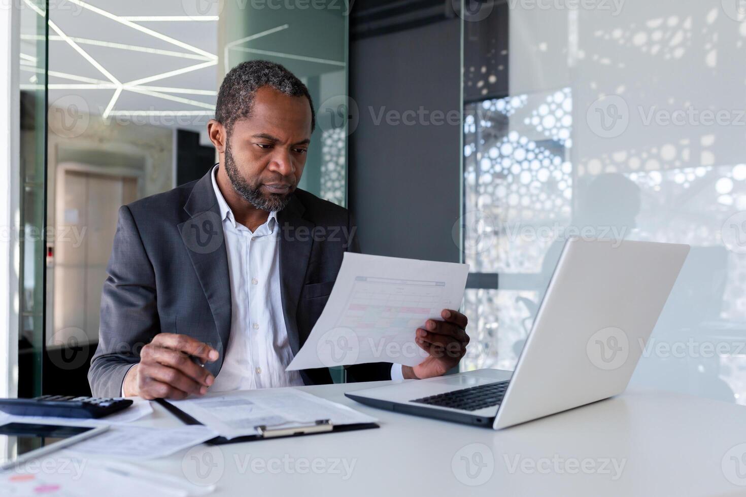 grave mayor experimentado financiero comprobación informes, africano americano empresario en negocio traje concentrando pensando trabajando con contratos y facturas, papeleo dentro oficina. foto