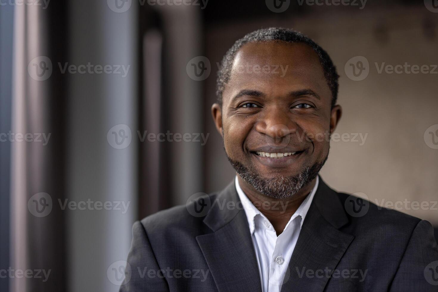 retrato de un positivo africano americano empresario con un calentar sonrisa, vestido en un formal traje, a un lugar de trabajo. foto