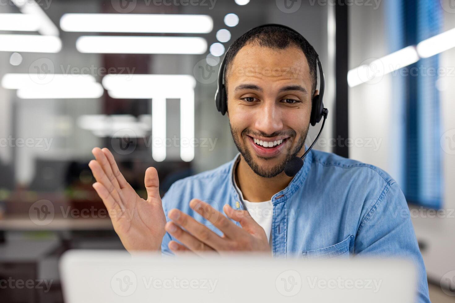 alegre masculino cliente Servicio representante vistiendo un auriculares y Hablando con un cliente en un moderno oficina ambiente. foto