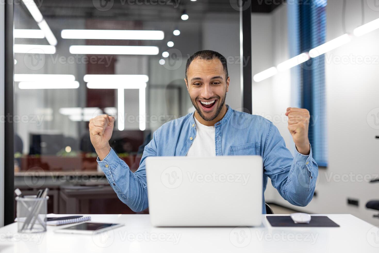 un jubiloso oficina trabajador celebra un exitoso momento, mostrando un positivo reacción con un puño bomba en un brillante oficina ajuste. foto