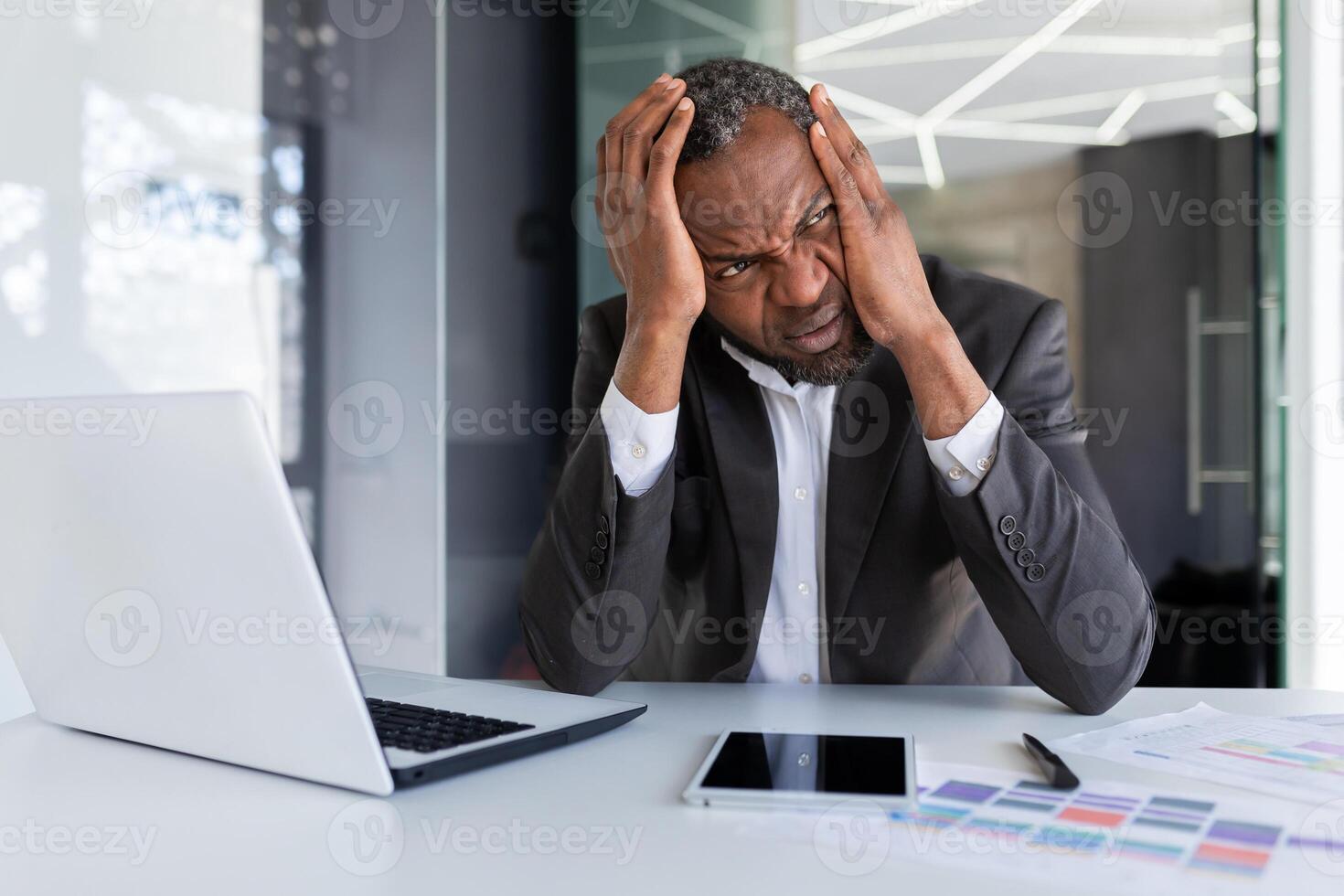 African american mature adult businessman upset in depression at workplace, senior man working in middle of office, unhappy with results of financial achievement banker investor photo