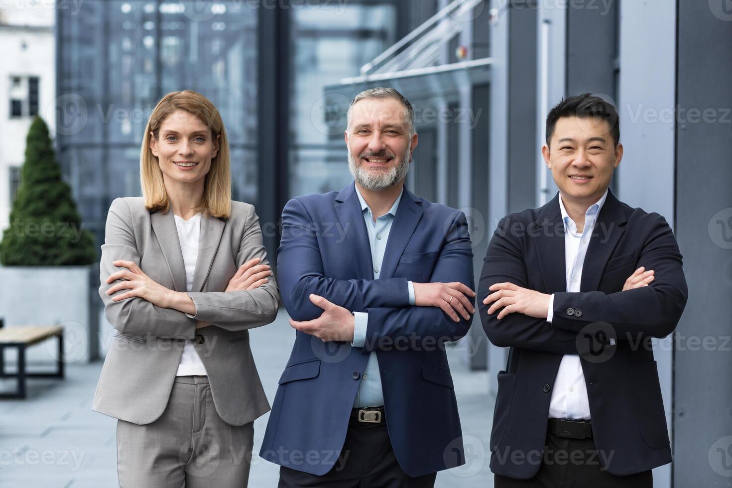 Successful dream team, diverse business group of asian man and business woman smiling and looking at camera, colleagues with crossed arms outside office building, professionals investors and bankers photo